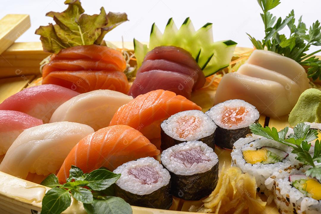 Mistura de comida japonesa, incluindo sushi e sashimi na barcaça de madeira.
