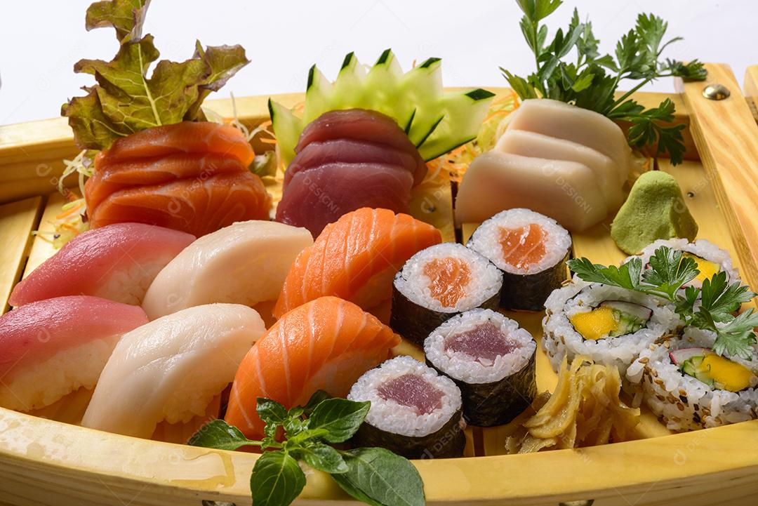 Mistura de comida japonesa, incluindo sushi e sashimi na barcaça de madeira.