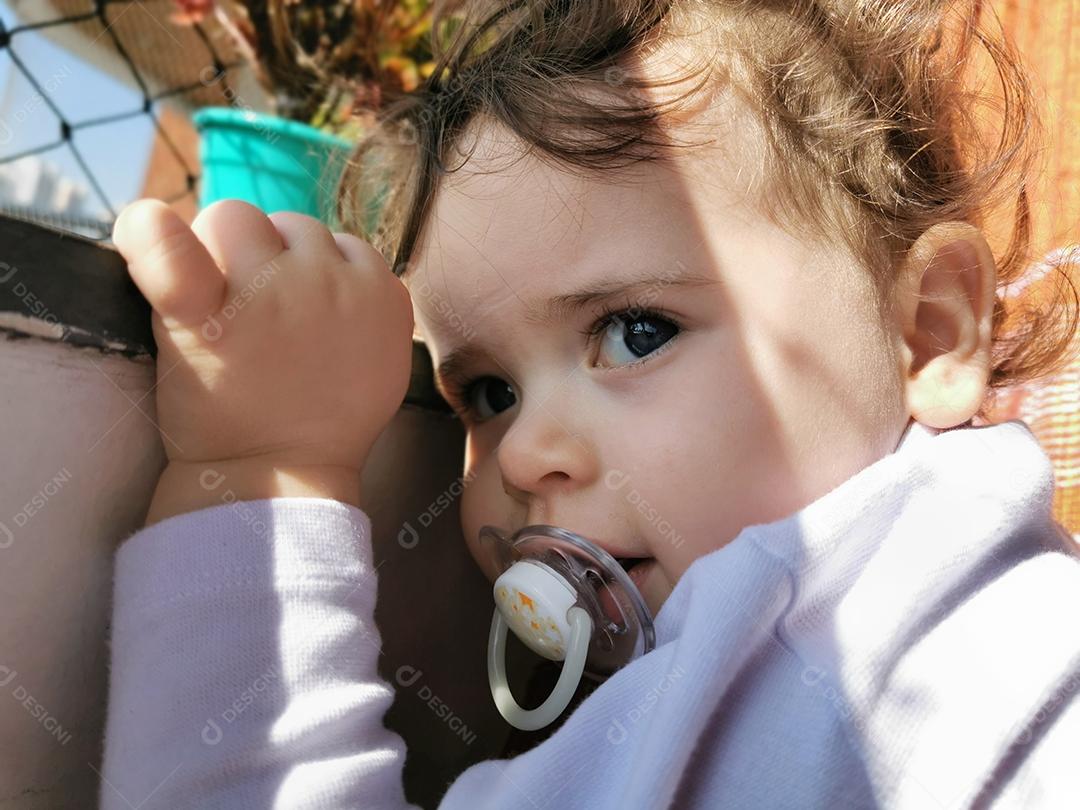 Bebezinho no verão na varanda atrás da rede de segurança.