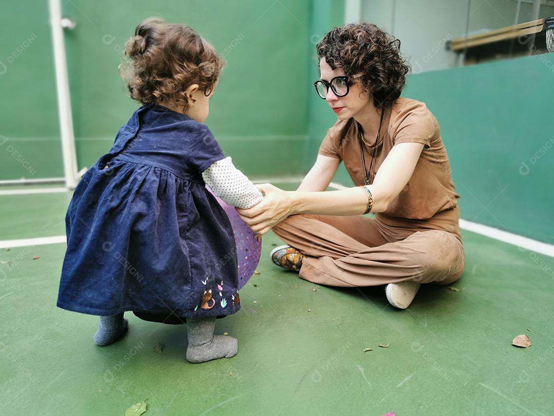 Mãe e filha jogando bola na quadra.