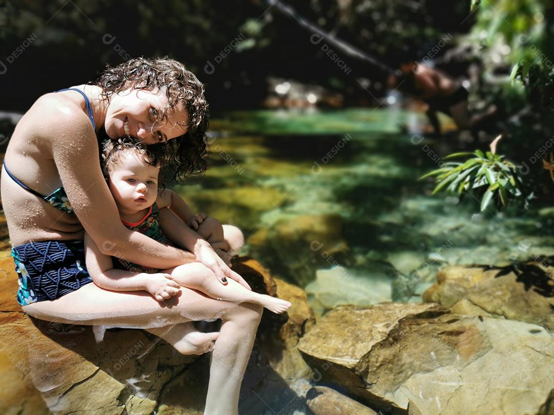 Mãe e filha se refrescando no verão na cachoeira.