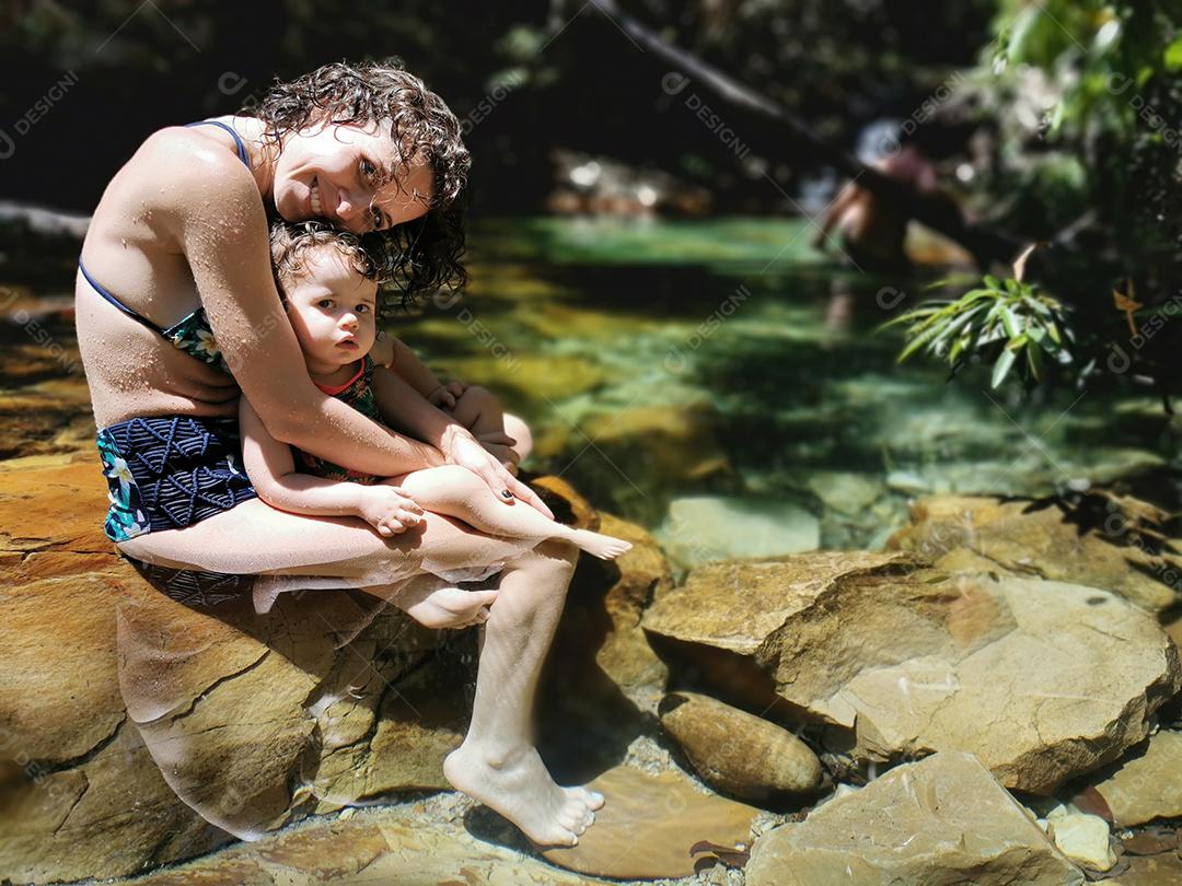 Mãe e filha se refrescando no verão na cachoeira.