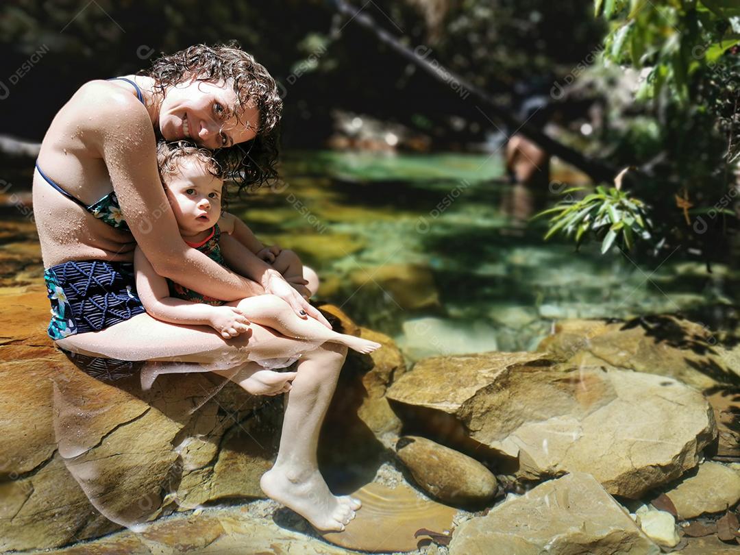 Mãe e filha se refrescando no verão na cachoeira.