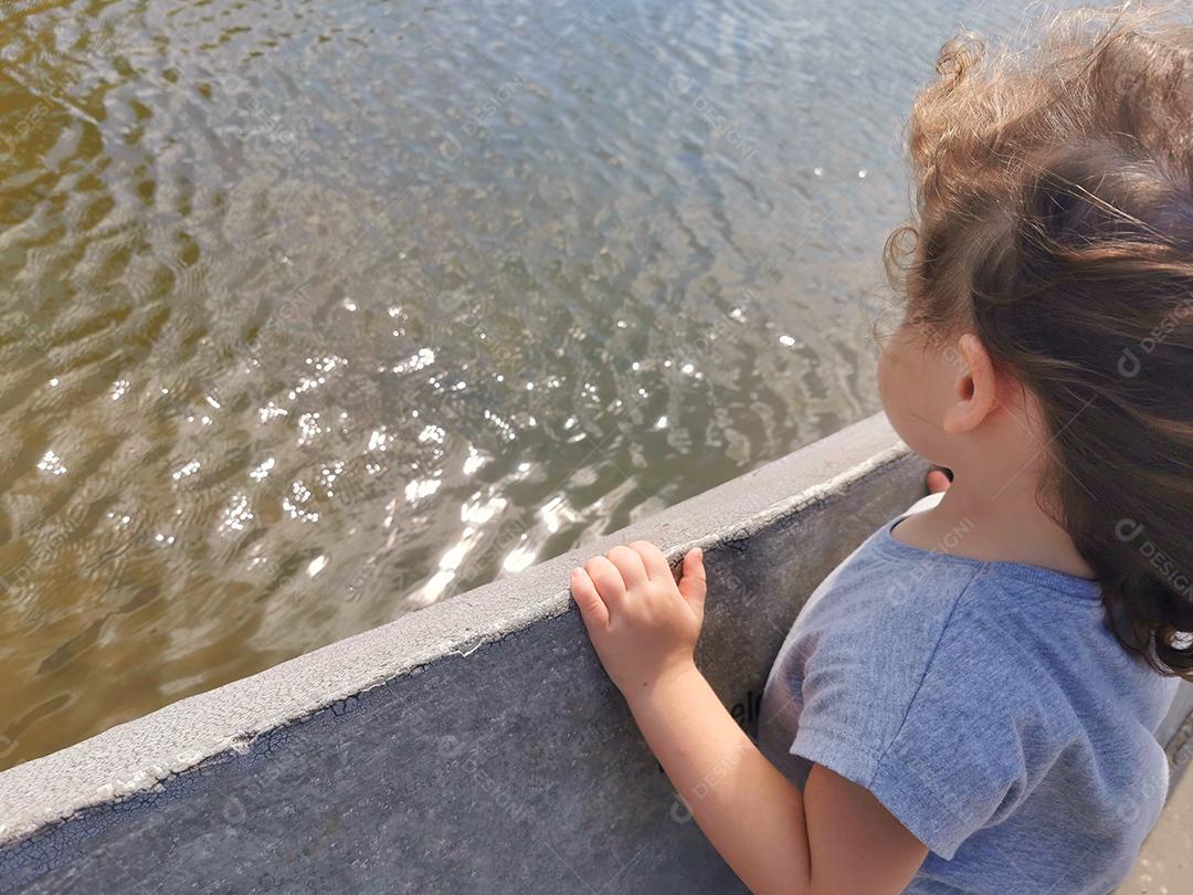 Menina brasileira observando as ondas da fonte ao vento..