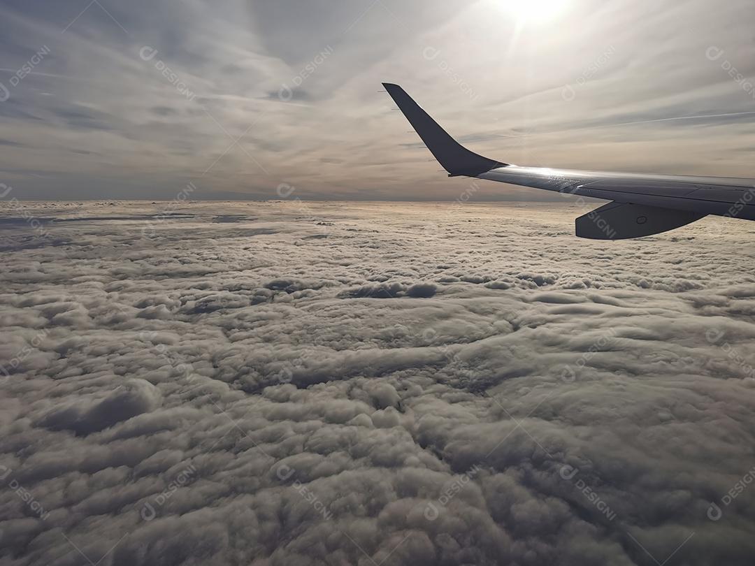 Vista aérea de nuvens fofas com o sol sob a asa do avião.