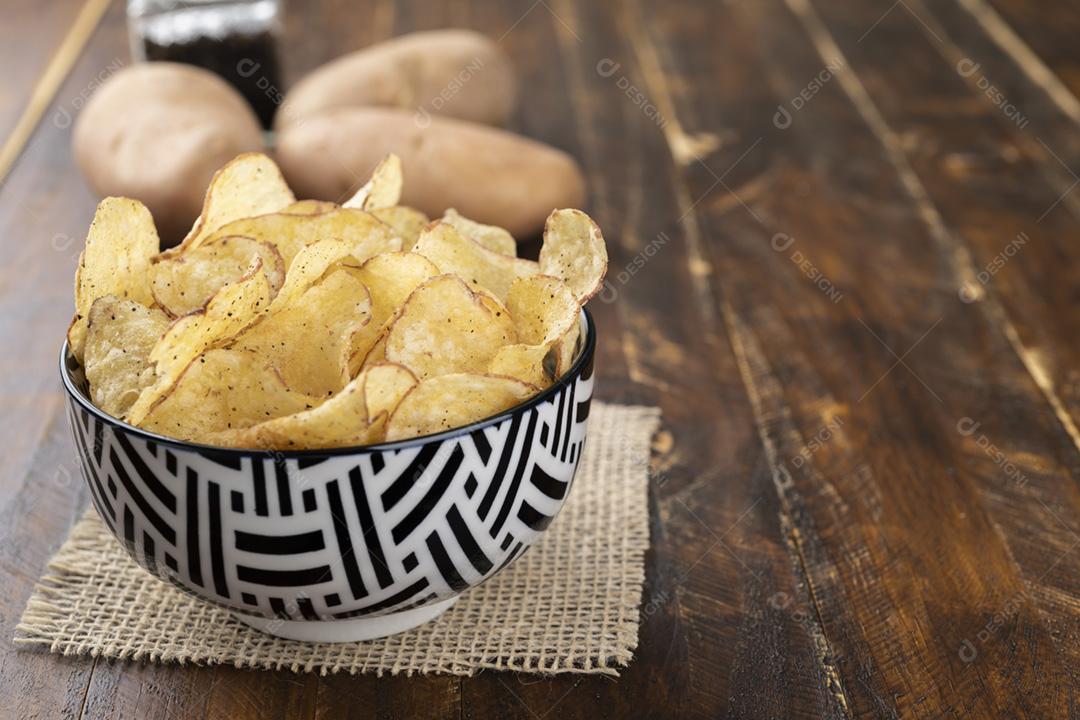 Tigela cheia de batatas fritas com batatas cruas, uma colher de sal e