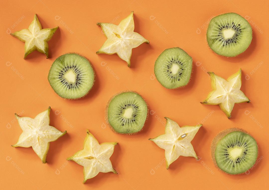 Starfuit e fatias de kiwi sobre fundo laranja