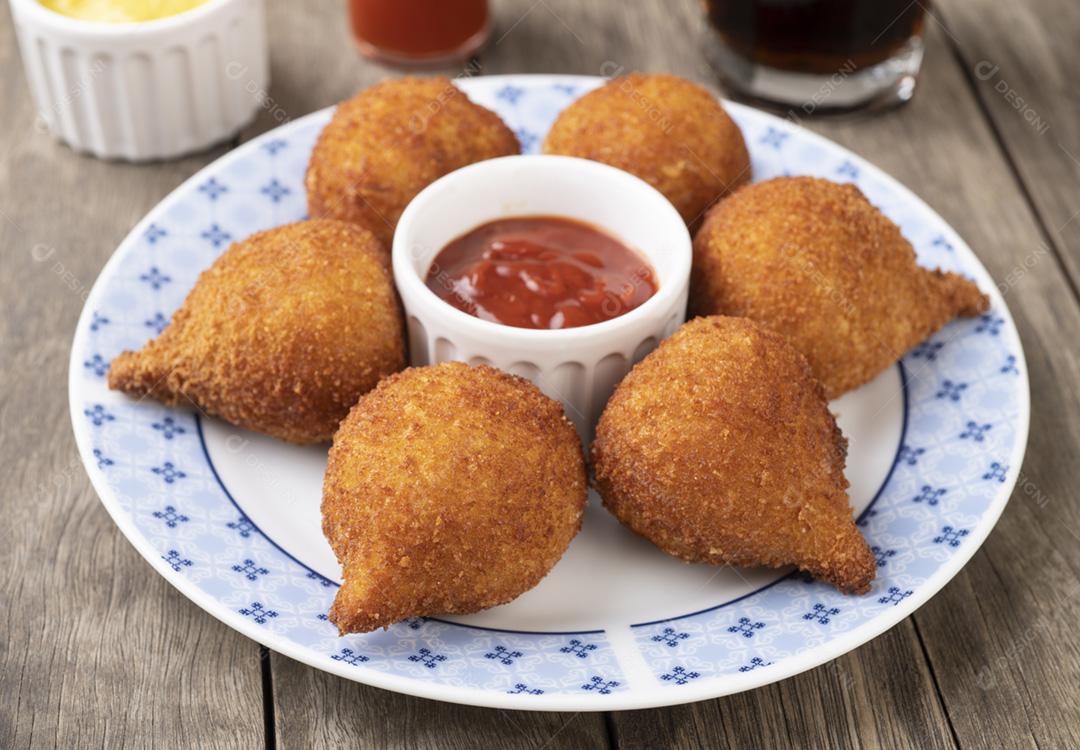 Coxinha de lanche típico brasileiro em um prato sobre a mesa de madeira