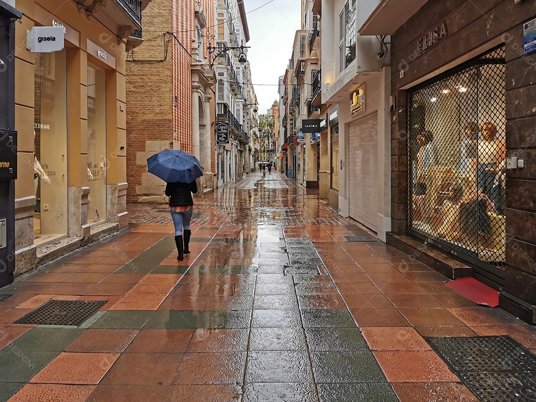 Málaga, Espanha - 21 de fevereiro de 2021: Vista de uma pessoa usando guarda-chuva nas ruas do Soho em Málaga em um dia chuvoso.