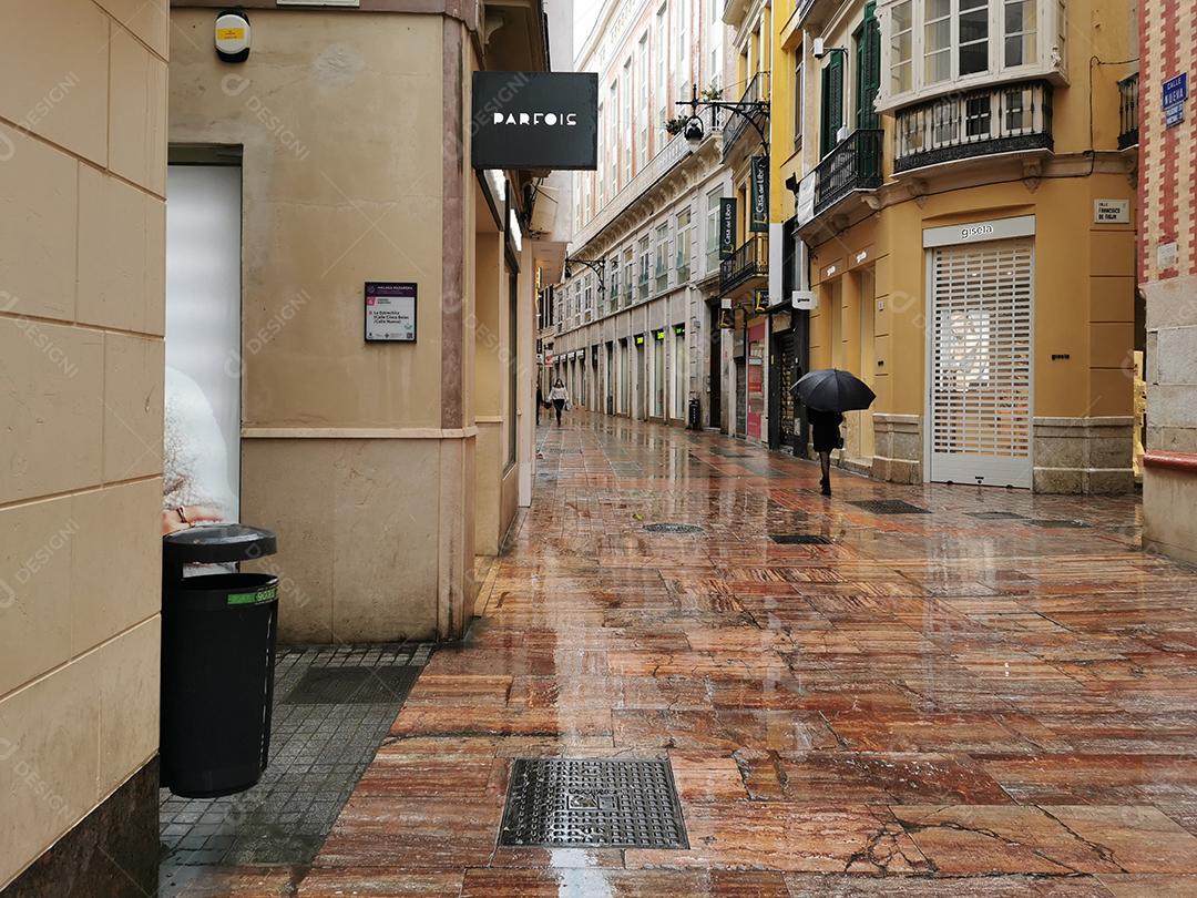 Vista de pessoa usando guarda-chuva nas ruas do Soho em Málaga em um dia chuvoso.