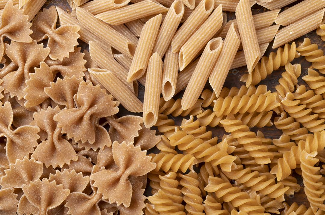 Vista superior, closeup de farfalle de trigo integral, penne e fusilli pas