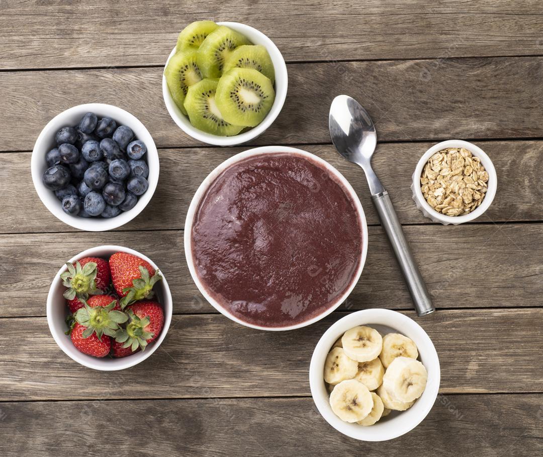 Tigela de açaí típica brasileira com frutas e muesli sobre b de madeira