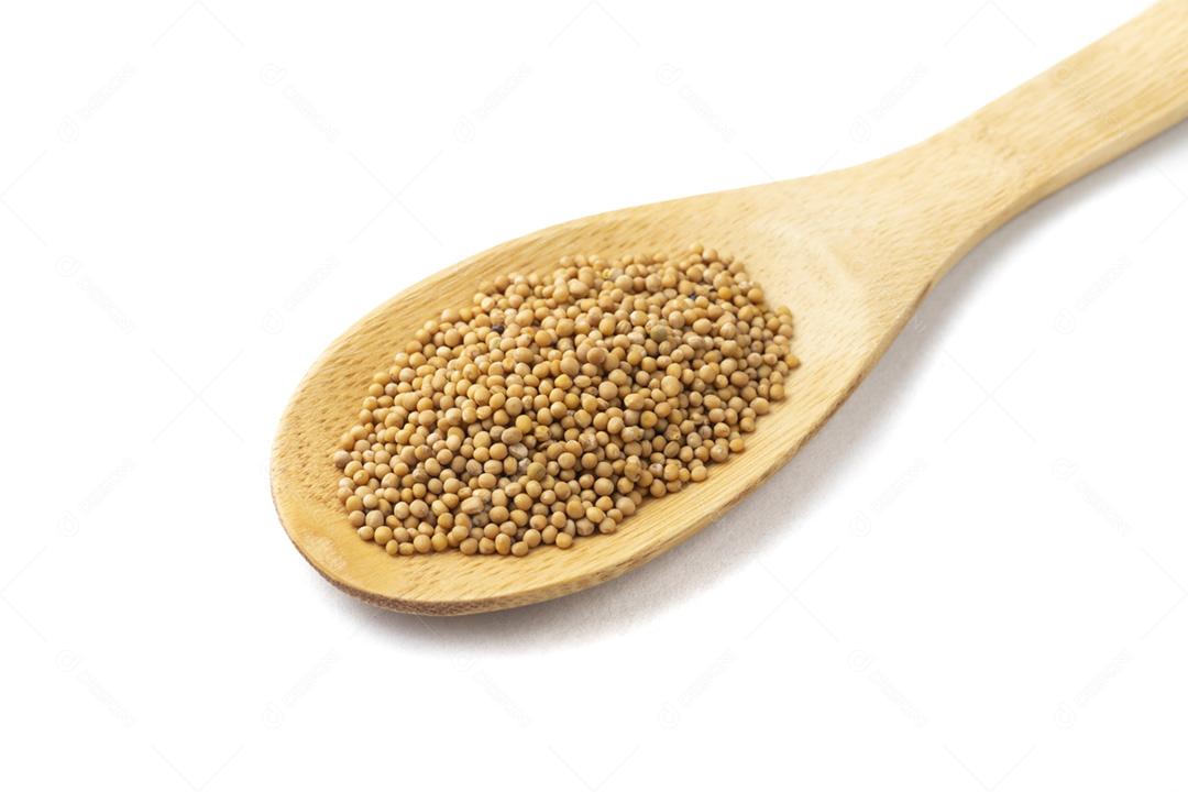 Closeup de semente de mostarda em uma colher de pau isolada sobre vagabundos brancos