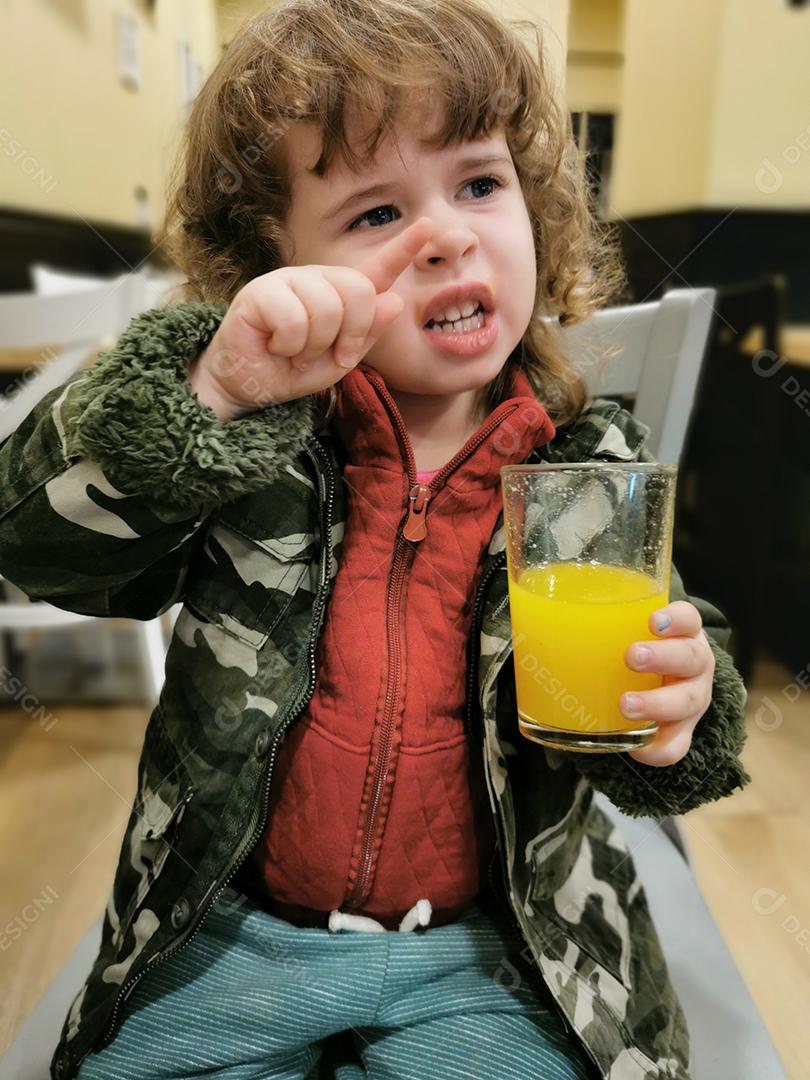 Vista da menina bebendo suco de laranja durante o inverno.
