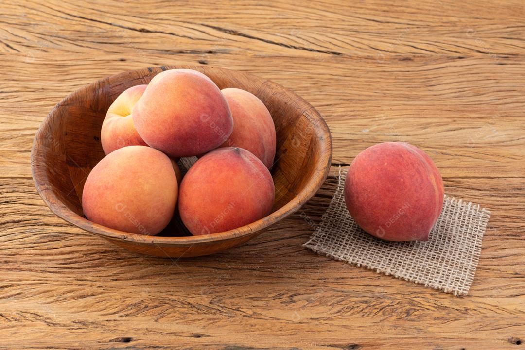 Pêssegos em uma tigela sobre a mesa de madeira