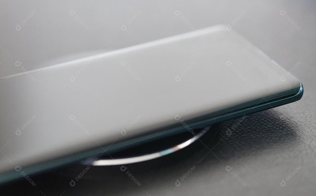 Vista próxima do celular sendo carregado sem fio com foco seletivo.