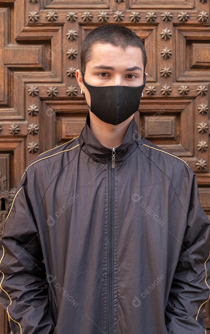 Jovem usando máscara facial olhando para a câmera durante a pandemia.