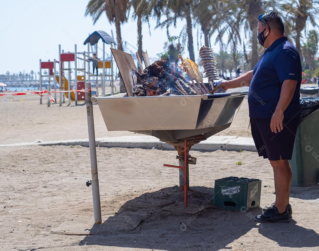 vista de uma churrasqueira preparando um espeto de peixe típico nas praias de Málaga.