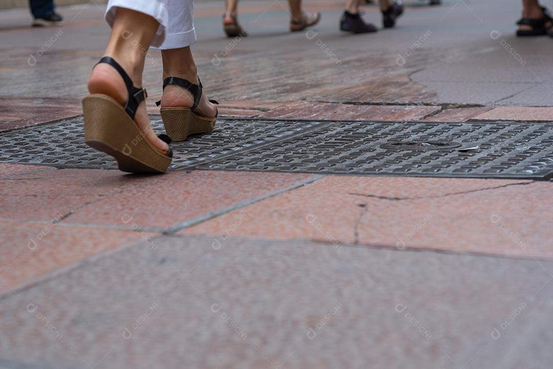 vista dos pés das pessoas andando na rua comercial..