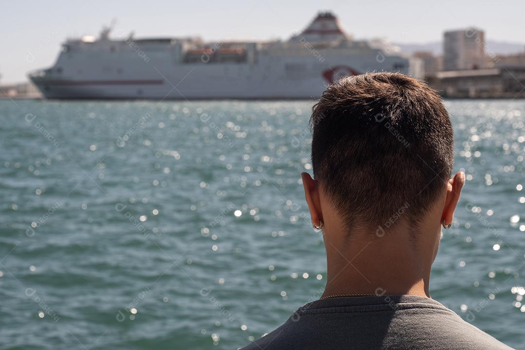 Vista de um adolescente no porto de Málaga, olhando para o mar.