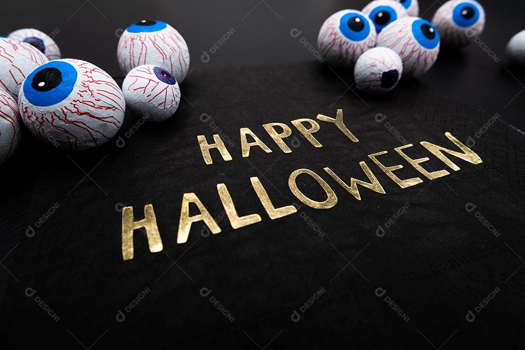 Funny Halloween treat - candy eyeballs with a napkin written Happy Halloween on dark background