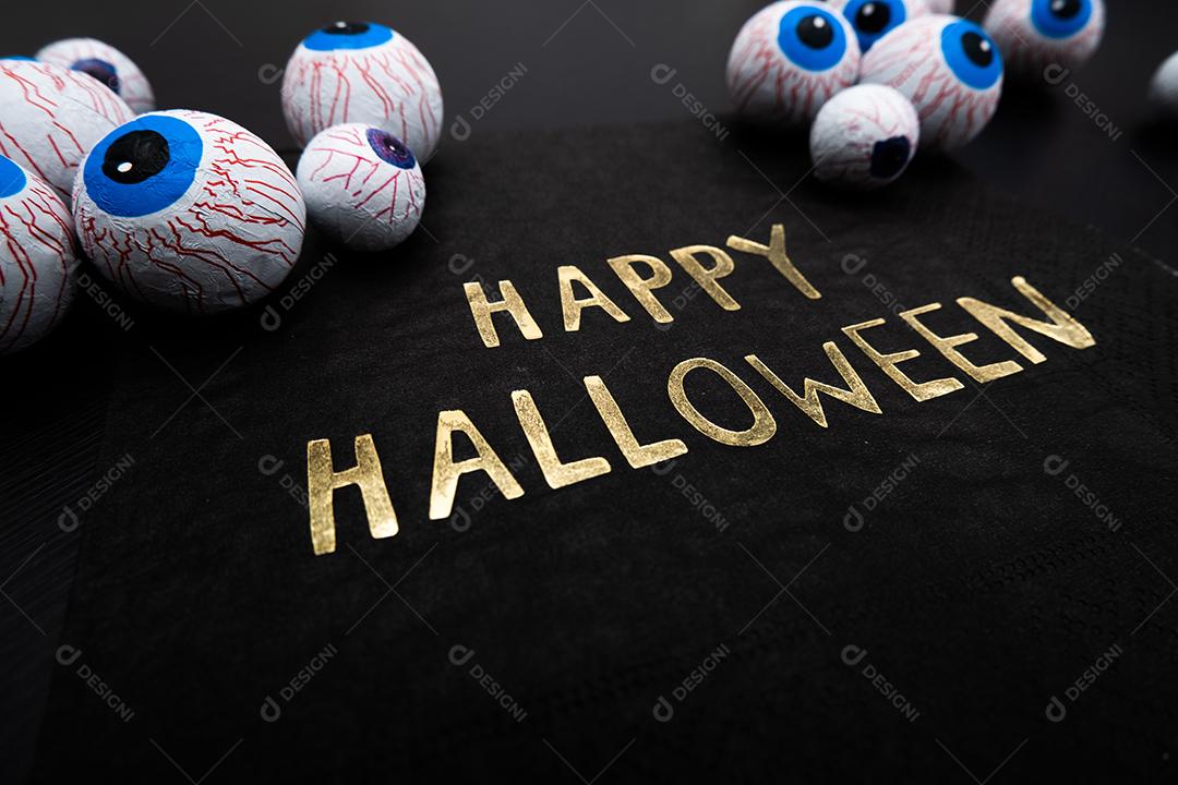 Engraçado deleite de Halloween - globos oculares de doces com um guardanapo escrito Feliz Dia das Bruxas em fundo escuro