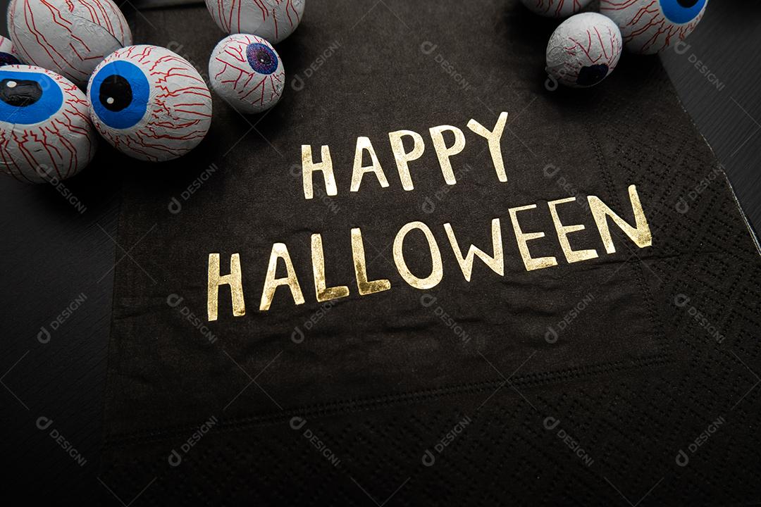 Engraçado deleite de Halloween - globos oculares de doces com um guardanapo escrito Feliz Dia das Bruxas em fundo escuro