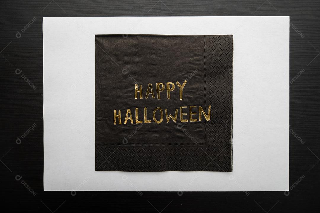 Vista superior um guardanapo escrito Feliz Dia das Bruxas em fundo escuro.