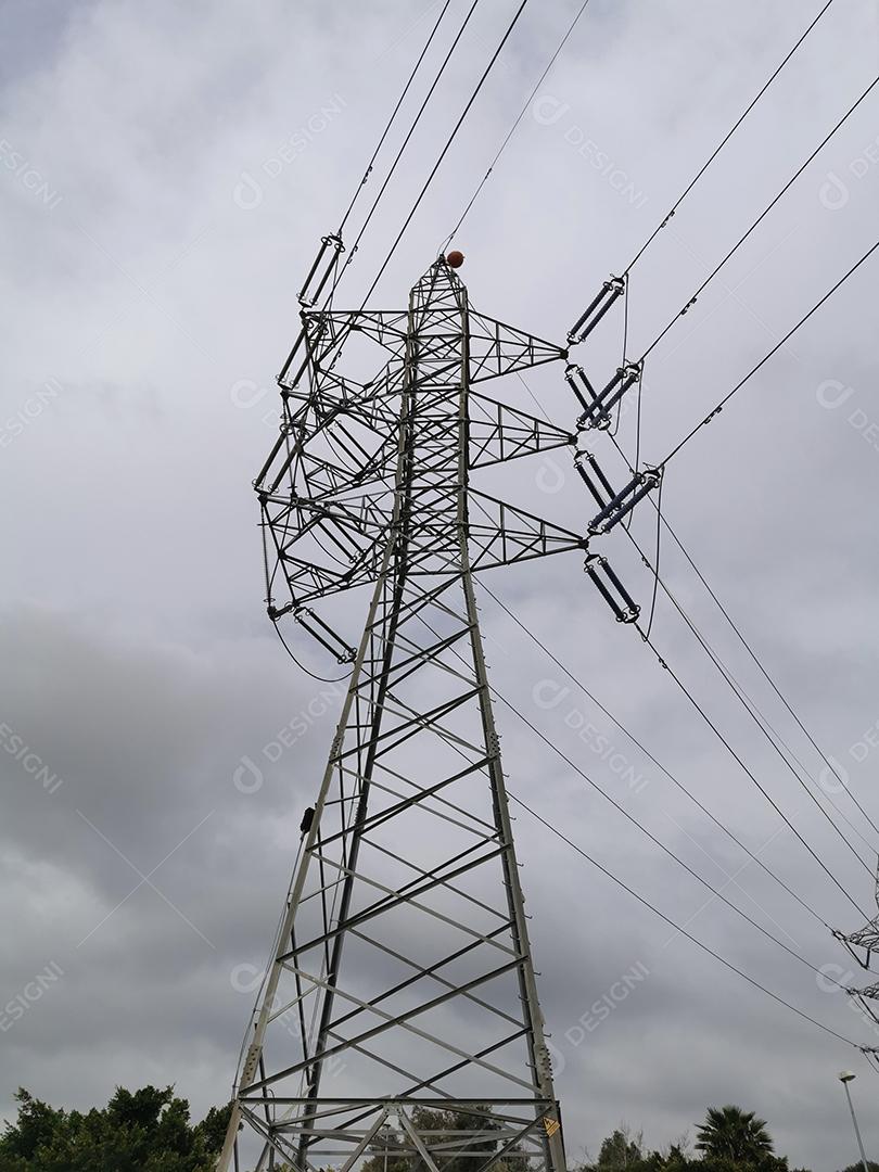 Vista vertical de uma torre de energia elétrica com céu com nuvens.