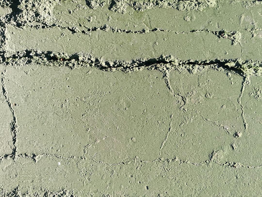 Vista da textura de cimento verde com rachaduras.