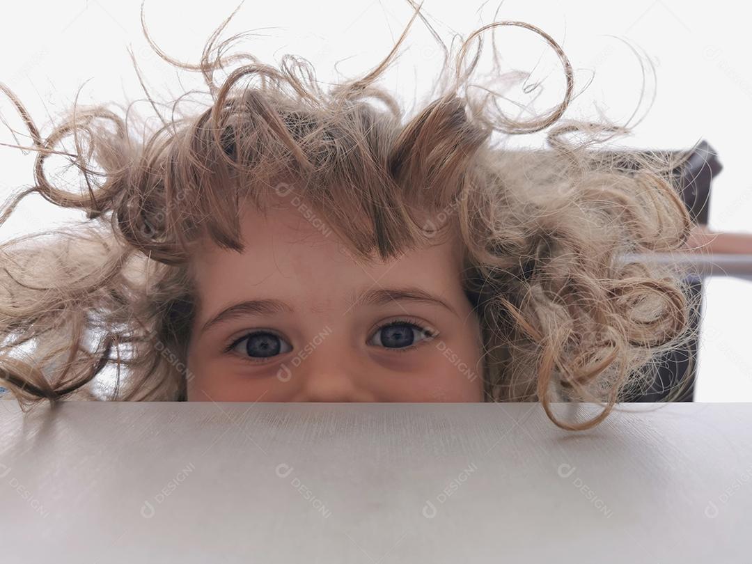 Foto engraçada com uma garotinha de cabelo encaracolado olhando para baixo