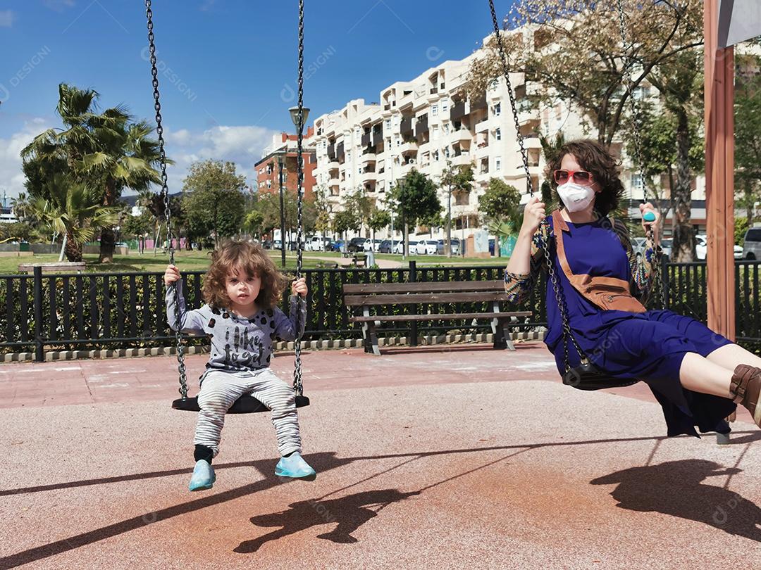 Málaga, Espanha - 02 de abril de 2021: Mãe e filha no parque brincando no balanço