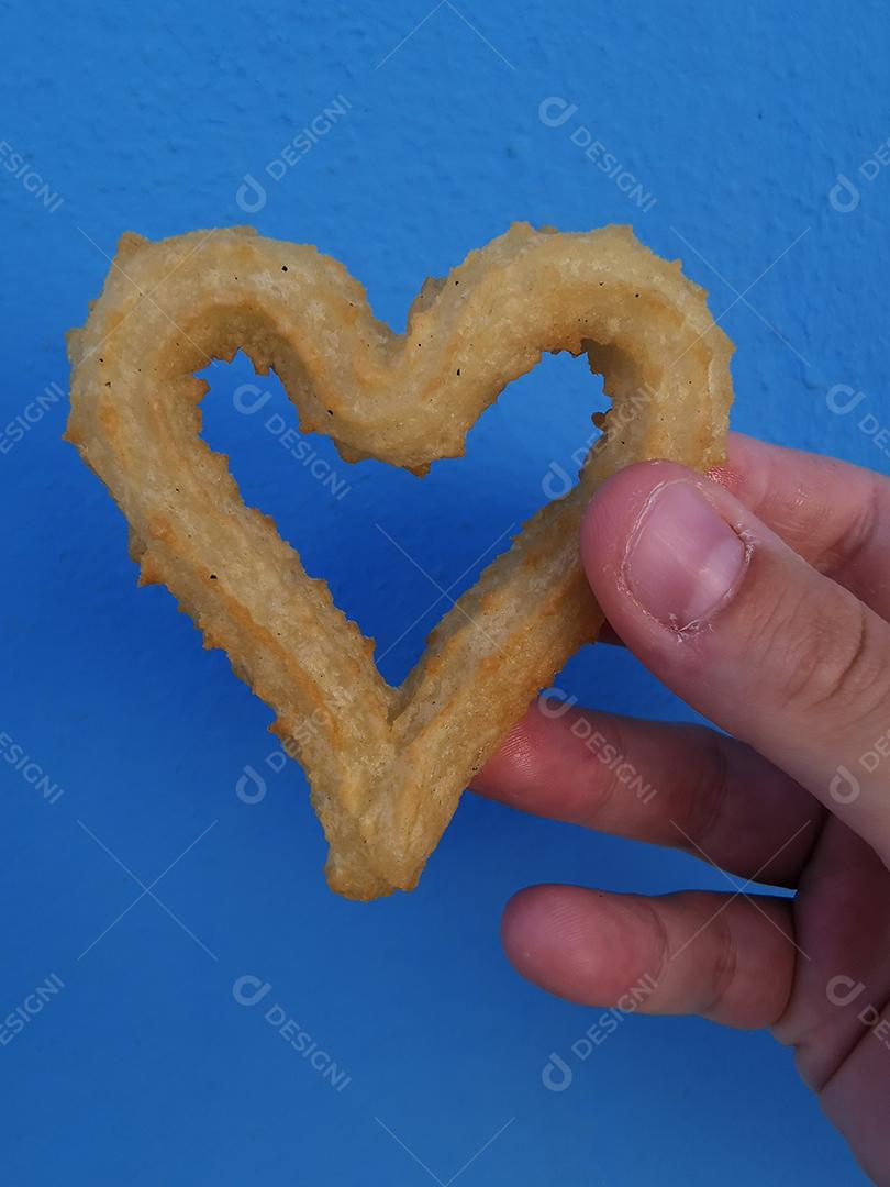 Churros em forma de coração sobre fundo azul.