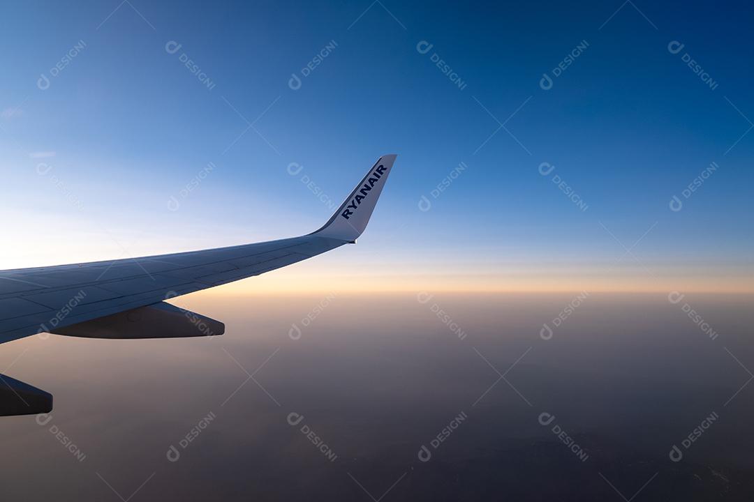 Bela vista pela janela do avião para a asa com o logotipo da Ryanair.