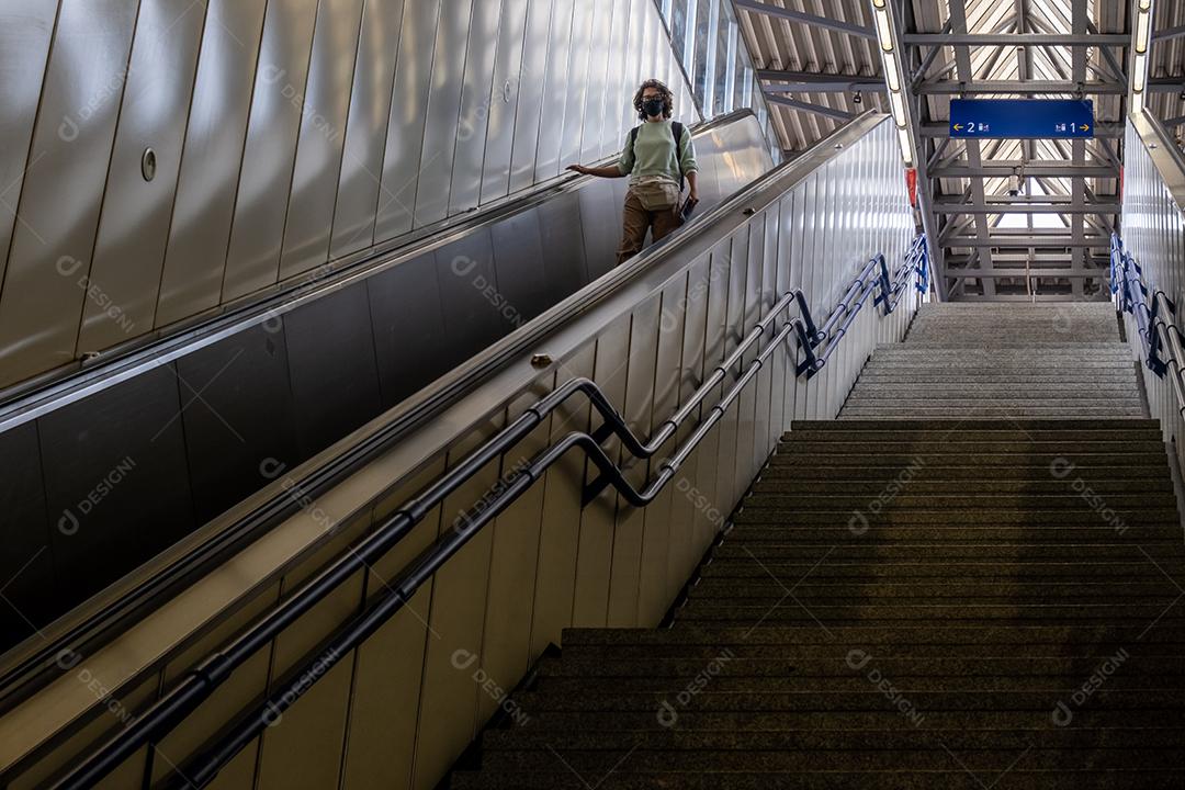 Mulher descendo a escada rolante do metrô em Viena.