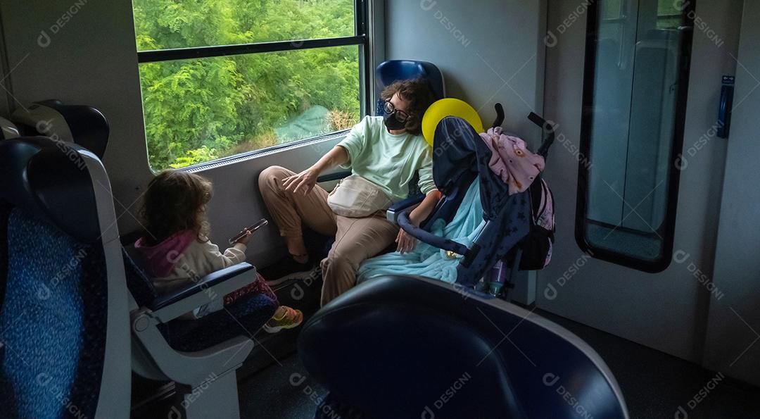 Mãe e filha viajando de trem.
