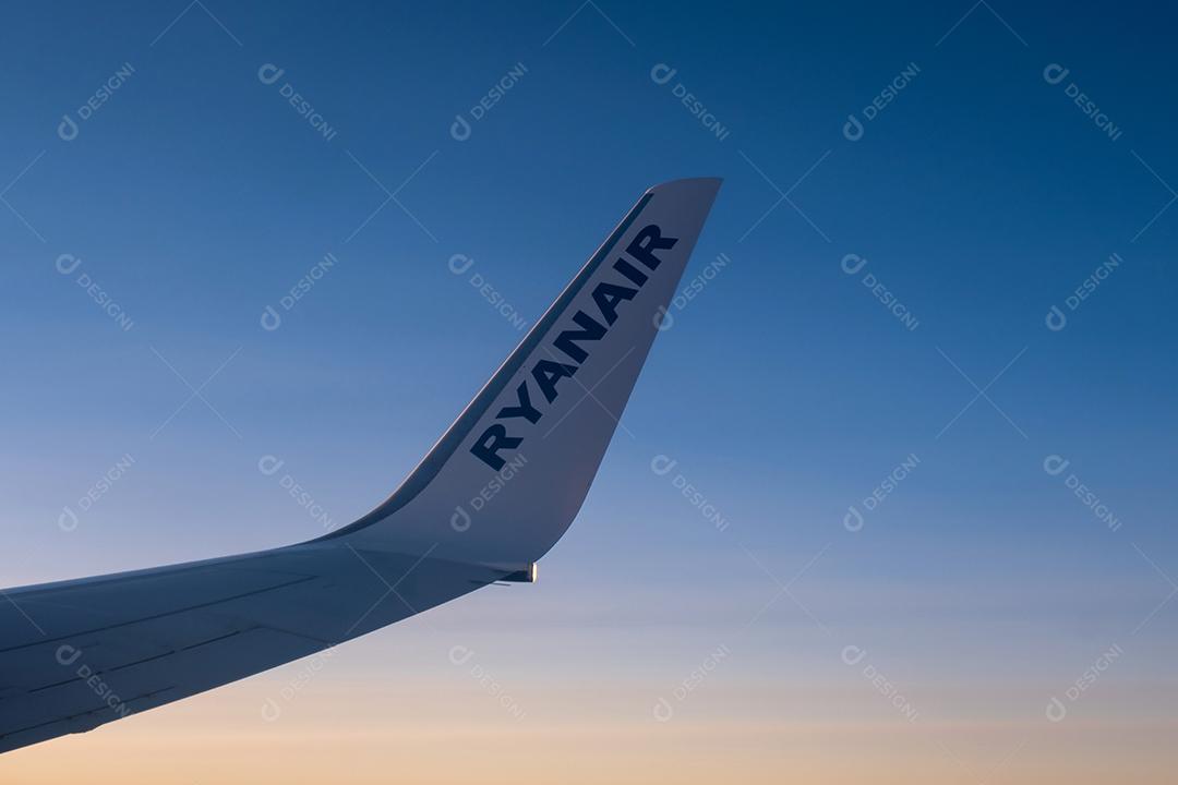 Bela vista pela janela do avião para a asa com o logotipo da Ryanair.