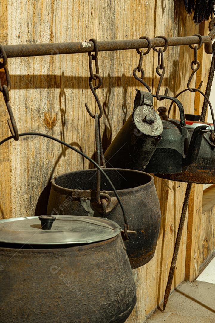 Panelas de ferro antigas penduradas em um suporte de ferro na cozinha da fazenda