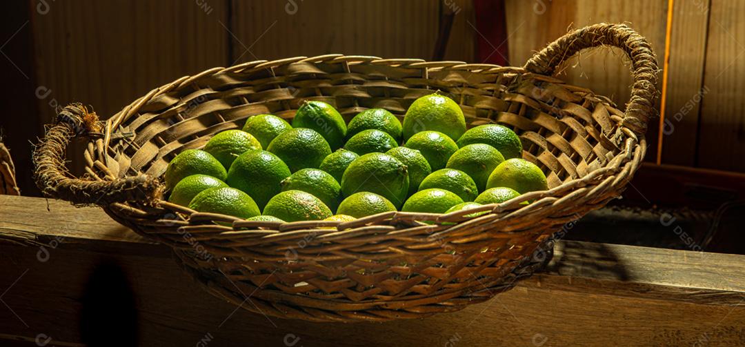 Cesta de palha com limões em cima de uma placa de madeira rústica