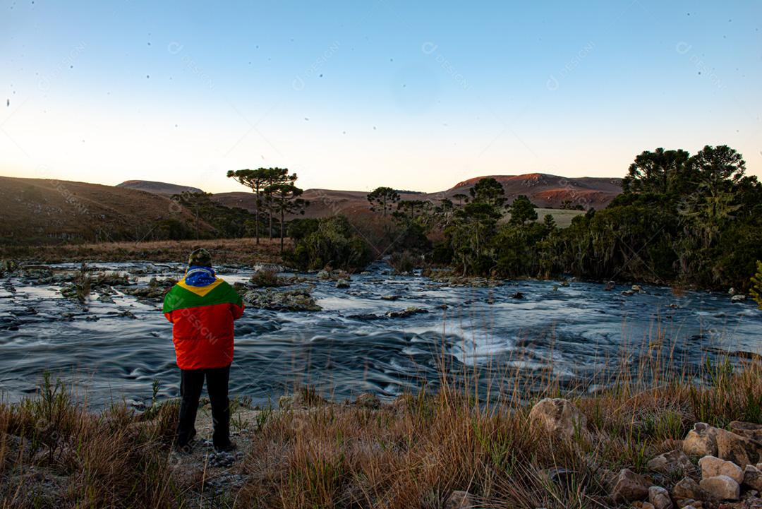 Um homem de pé aponta para a margem de um belo rio.