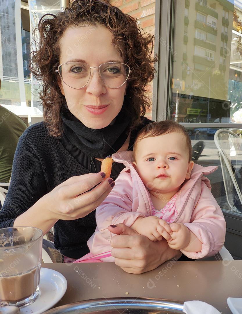 Mãe e bebê comendo churros em Málaga, Espanha.