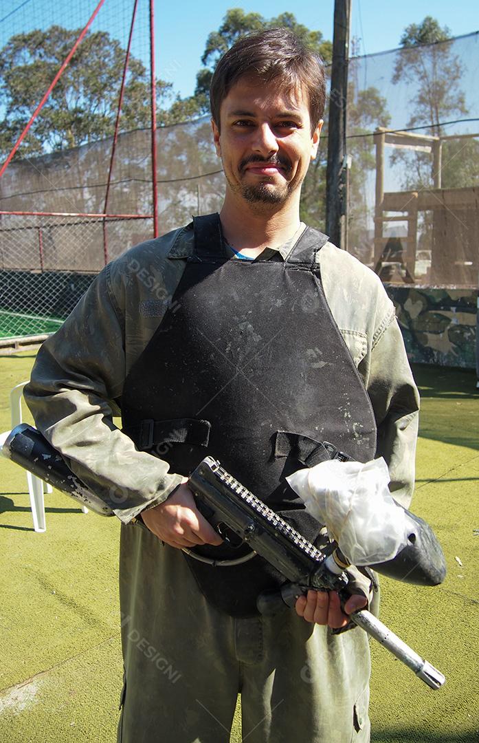 Jovem segurando uma arma de paintball se preparando para jogar