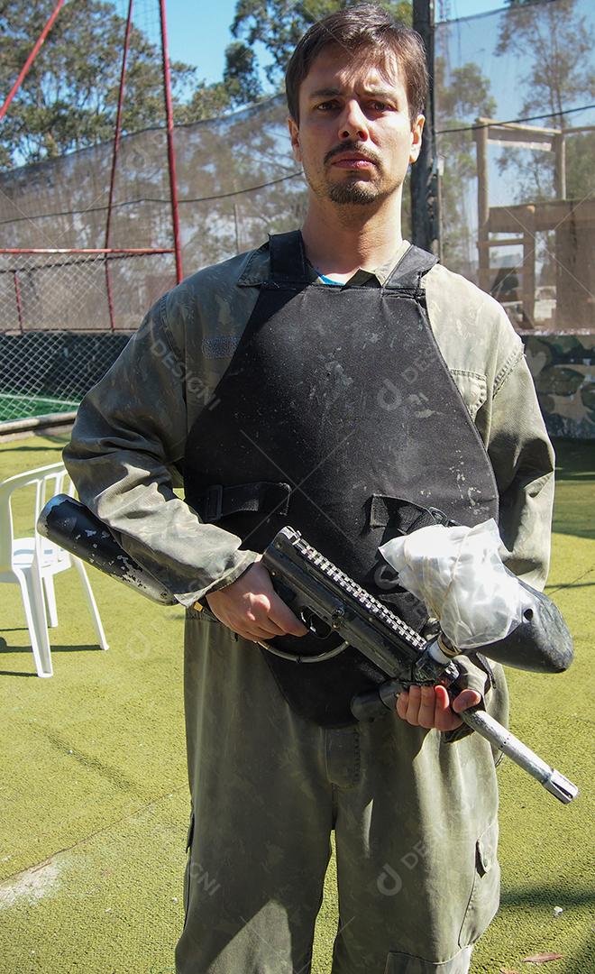 Jovem segurando uma arma de paintball se preparando para jogar