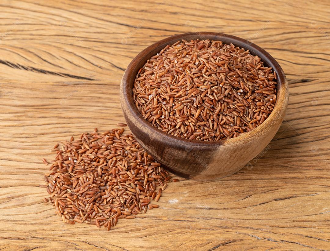 Arroz inteiro vermelho cru em uma tigela sobre a mesa de madeira.