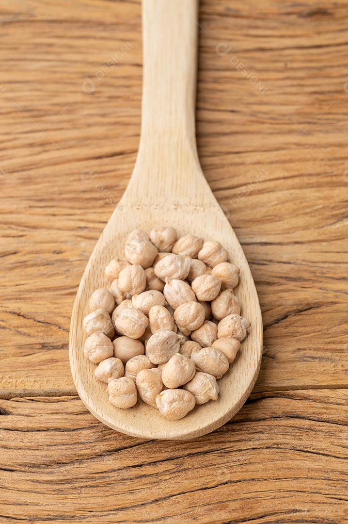 Grão de bico em uma colher sobre a mesa de madeira.