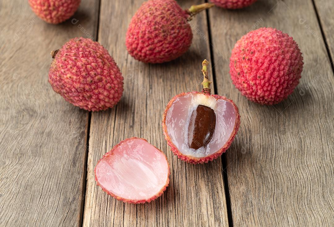 Lichias cortam frutas sobre a mesa de madeira.