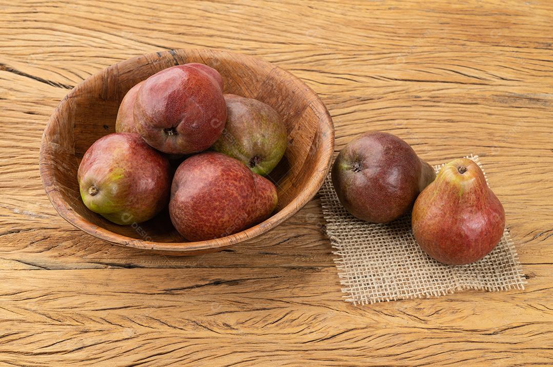 Peras vermelhas em uma tigela sobre a mesa de madeira.