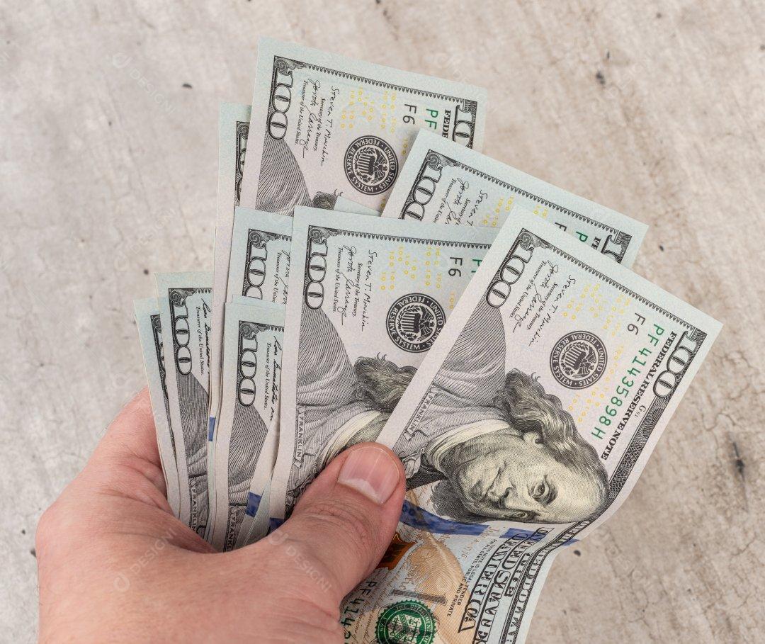 Mão segurando várias notas de dolar