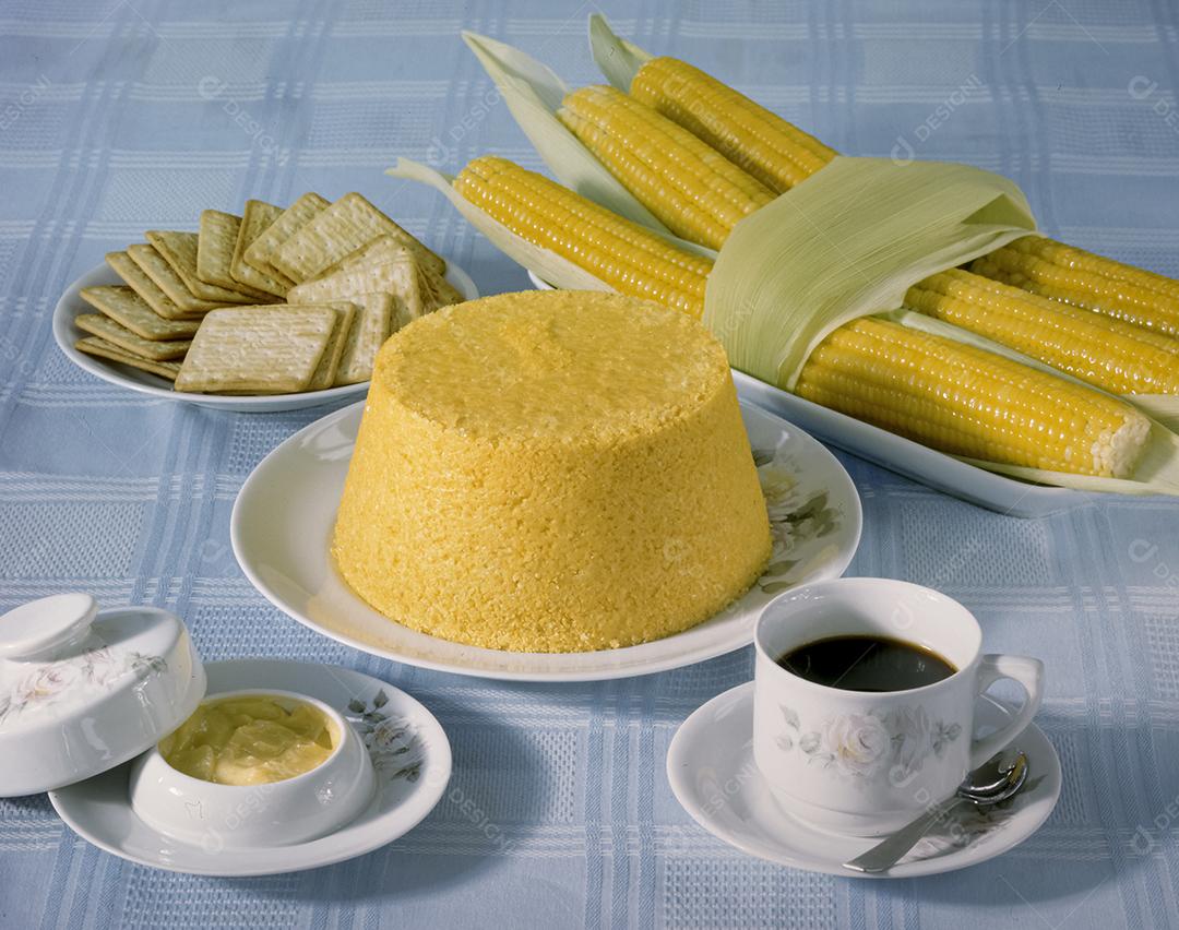 Cuscuz de milho à mesa com uma xícara de café e espigas de milho cozidas. Comida típica da região nordeste do Brasil.