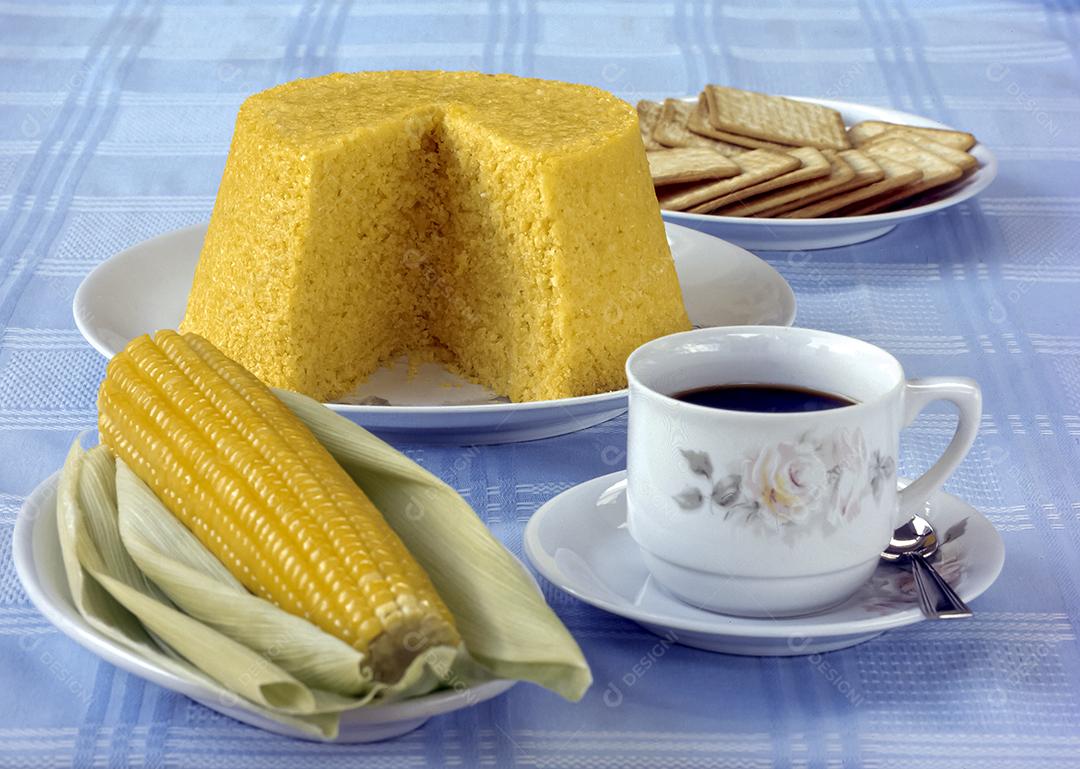 Cuscuz de milho à mesa com uma xícara de café e espigas de milho cozidas. Comida típica da região nordeste do Brasil.